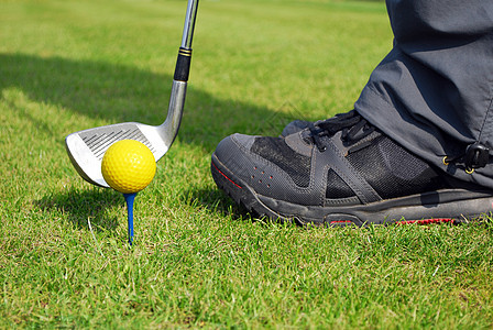 高尔夫球准备击打黄色高尔夫球绿色俱乐部闲暇运动鞋运动游戏图片