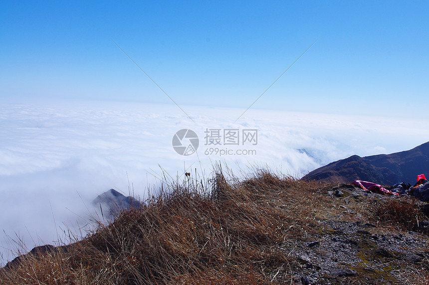 高山的山坡周围有云天空青金石稻草岩石登山者风景旅行多云高地杂草图片