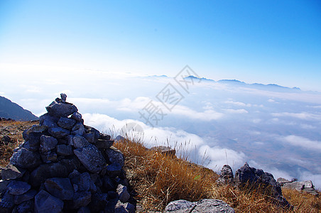 高山的山坡周围有云青金石登山者旅行稻草羽绒被游客山腰高地太阳天空图片