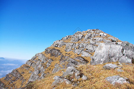 高山顶顶有岩石和草地青金石杂草稻草石头山顶登山高地山腰天空多云图片