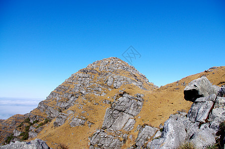 高山顶顶有岩石和草地羽绒被高地登山太阳顶峰悬崖峭壁旅行石头天空稻草图片