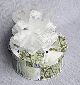 在一个圆箱里送的礼物 在灰色背景上有一个弓圆形盒子绿色白色纸板玫瑰乐趣黄色蓝色惊喜图片