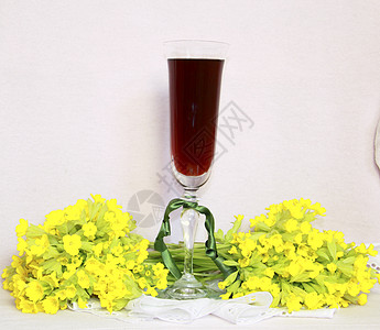 一杯杯子 红酒在薄纸巾和一束黄色花朵上白色花束餐巾织物粉色鞋带酒杯场地绿色磁带图片