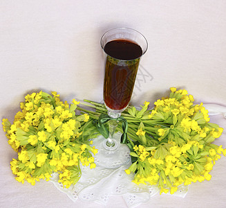 一杯杯子 红酒在薄纸巾和一束黄色花朵上花束红色酒杯绿色织物白色磁带场地鞋带餐巾图片