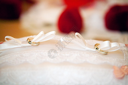 金婚戒指在针缝上白色珠宝新娘说谎花边软垫红色枕头蕾丝风俗图片