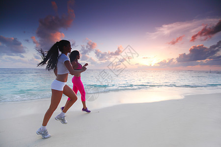 两个女人在沙滩上奔跑蓝色慢跑者赛跑者天空慢跑海滩海洋运动装训练女性图片