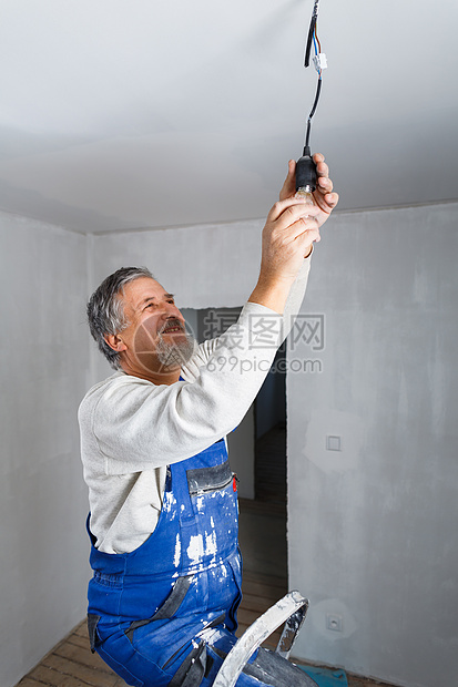 年长者在新装修的公寓内安装灯泡检修男人电缆修复工人工匠工艺梯子翻拍改装图片