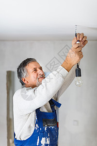 年长者在新装修的公寓内安装灯泡梯子整容翻拍电工现代化电气修复工人工具改装图片