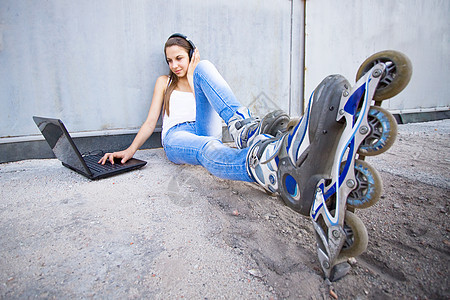 穿滚鞋的女孩青少年蓝色运动女士牛仔裤音乐微笑乐趣笔记本耳机图片