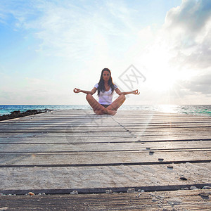 近海边的瑜伽妇女冥想运动女孩卫生天空码头阳光场景孤独禅意成人图片
