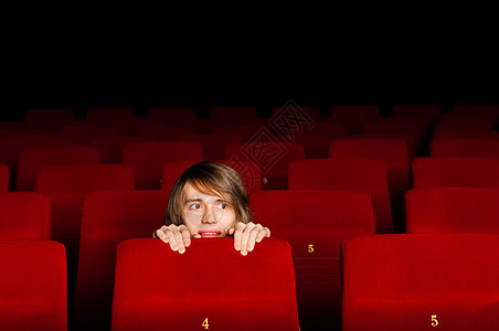 在电影院的年轻人 躲在椅子后面投影观众男生乐趣青少年大厅男人夫妻电影微笑图片