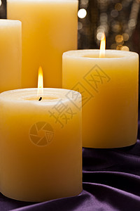 紫天鹅绒上四根蜡烛烛光火焰辉光点燃织物柱状天鹅绒丝绸浪漫礼物图片