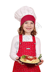 快乐的小女孩烹饪 小女孩做饭与意大利面白首席青年孩子美食帽子女孩食物盘子童年午餐图片