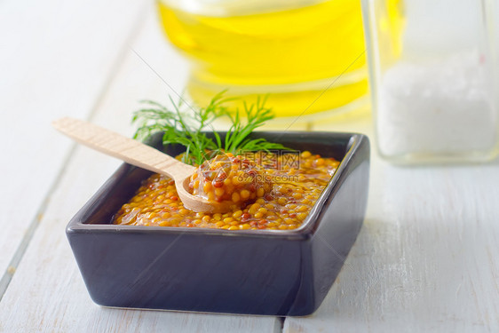 桌上黑碗里的芥末勺子播种种子香料味道粮食伴奏玻璃粉末芸苔图片