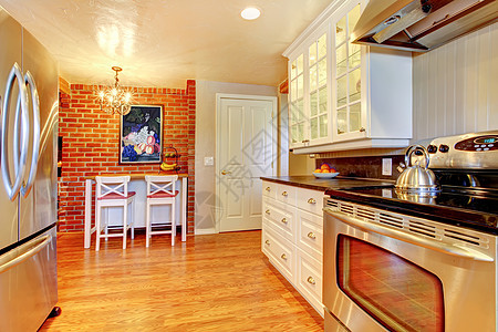 白色厨房有砖墙 硬木和不锈的偷炉子橱柜台面木头凳子家电壁炉火炉房地产冰箱家具图片