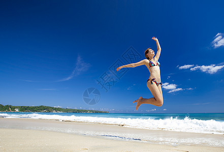 女人在海滩上跳跃喜悦海洋女性游泳衣跑步天空乐趣身体热带闲暇图片