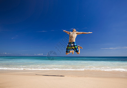男人在海滩上跳跃成功热带假期自由蓝色幸福身体天空成人游泳衣图片
