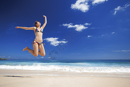 女人在海滩上跳跃天堂成功成人海洋棕褐色乐趣热带比基尼旅行跑步图片