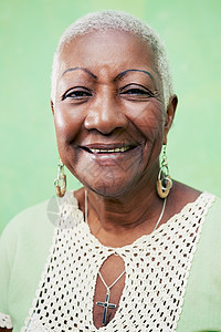 高级黑人女性的肖像 在绿色背面对着镜头微笑情绪老年人幸福快乐老年女士黑色退休耳环相机图片