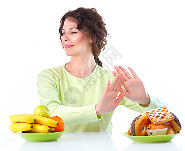 美丽的年轻女子在水果和甜甜之间选择食物垃圾蛋糕损失营养女士思维巧克力香蕉身体馅饼图片