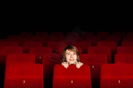 在电影院的年轻人 躲在椅子后面乐趣金发闲暇喜剧男性娱乐夜生活电影幸福男人图片