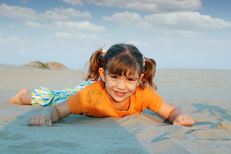 快乐的小女孩躺在沙地上图片