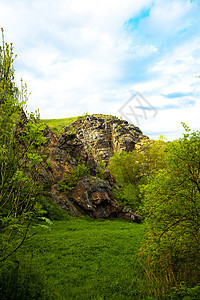 用绿色的岩石对着蓝色的天空和云彩风景环境树木土地叶子森林爬坡场景苔藓旅行图片