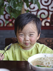 可爱的宝宝在吃东西童年面条托盘男生肩膀食物孩子后代摄影图片