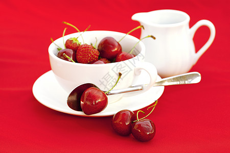 奶茶壶 酱汁勺子樱桃和草莓 在红色的背面水壶活力叶子杯子水果剪裁牛奶盘子宏观用具图片