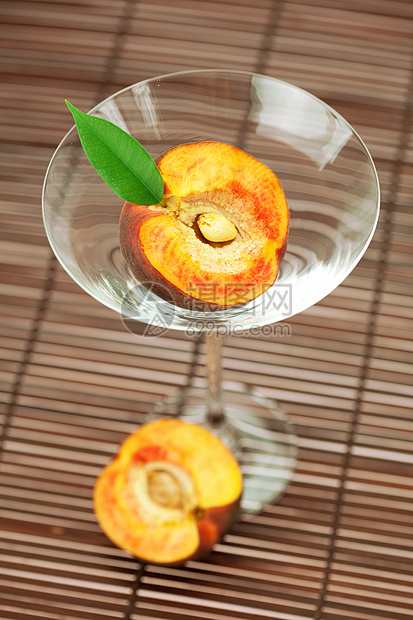玛蒂尼酒杯中的桃子 在竹垫上材料玻璃条纹木头食物黄色红色橙子棕色圆圈图片