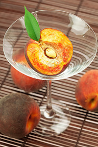 玛蒂尼酒杯中的桃子 在竹垫上条纹水果食物木头阴影材料红色玻璃曲线棕色图片