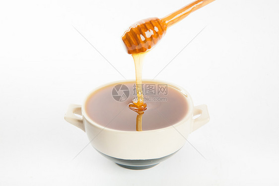 杯子和勺子里多汁的蜂蜜金子玻璃营养液体产品静物流动甜点美食木头图片
