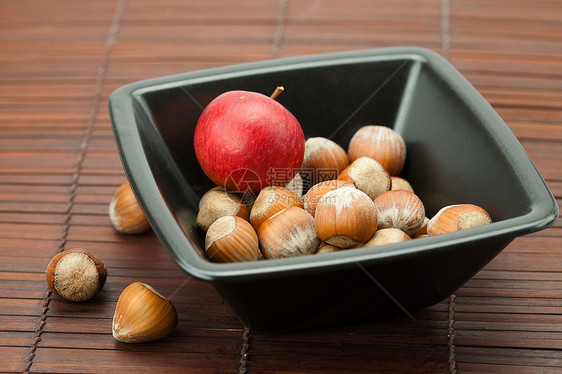 碗里的栗子和竹垫上的苹果宏观坚果圆圈木头摄影食物竹子力量工作室榛子图片