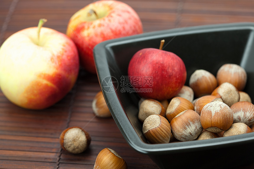碗里的栗子和竹垫上的苹果小吃种子圆圈榛子餐具宏观食物木头美食力量图片