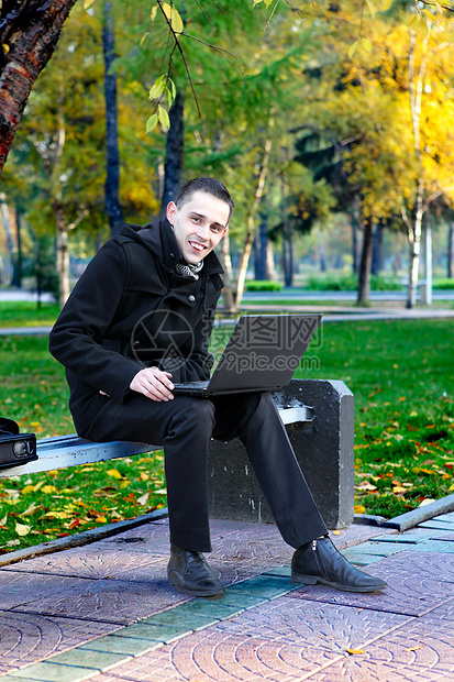 门外有膝上型电脑的人快乐工具面漆笔记本男性小路长椅外套工作公园图片