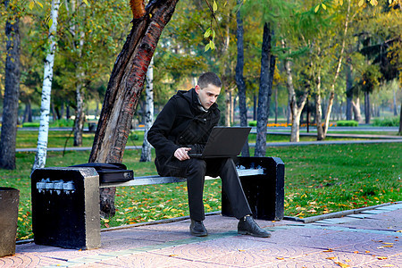 门外有膝上型电脑的人沉思头发互联网男性面漆笔记本外套叶子公园操作图片