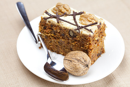 一小块蛋糕 坚果和勺子 躺在盘子上熟食榛子巧克力早餐餐具织物食物甜点摄影奶油图片