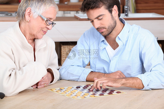 青年男子与年长妇女玩游戏男人游戏个人选址帮助成人跳棋微笑女士老年图片