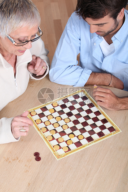 高级妇女与一名青年男子打棋图片