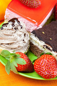 橙色织物上躺着的草莓和蛋糕盘子浆果巧克力叶子糖果水果坚果柠檬美食奶油图片