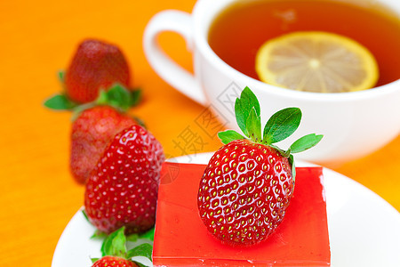 柠檬茶 蛋糕和草莓 放在橙色织物上文化巧克力早餐橙子液体坚果浆果柠檬糕点糖果图片
