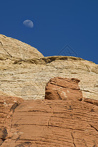 月亮在红岩峡谷上空升起月球岩层石头橙子蓝色天空侵蚀编队岩石山脉图片
