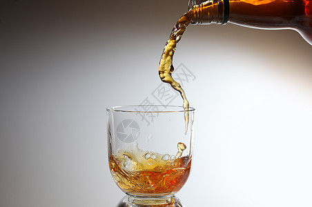 威士忌倒在玻璃杯里玻璃飞溅液体流动瓶子图片