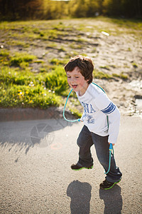 男孩玩跳绳黄金男生晴天青年时段孩子童年绳索男性街道图片
