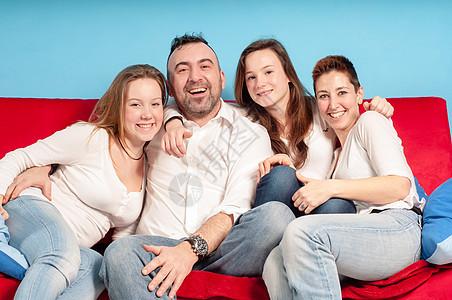 幸福的家庭在沙发上父亲牛仔裤女性女儿乐趣女孩男生母亲感情青少年图片