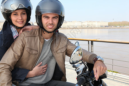 在河边骑摩托车的年轻夫妇图片