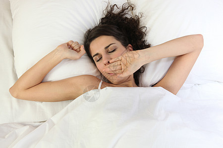 女人在床上醒来女性睡意头发枕头羽绒被时间眼睛房间困倦卧室图片
