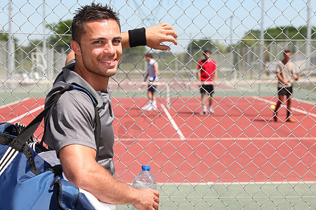 球场上的网球手玩家铁丝网游戏微笑训练水瓶男人娱乐晴天休息图片