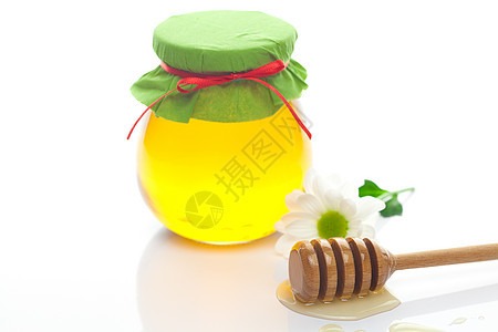 紧紧粘在白色上隔着的蜂蜜 花和罐子薄雾雏菊香味甜点药品洋甘菊早餐糖浆玻璃金子图片