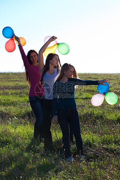 三名美丽的年轻女子 带着气球进入田野对抗幸福天空团体头发草地太阳友谊乐趣阳光微笑图片
